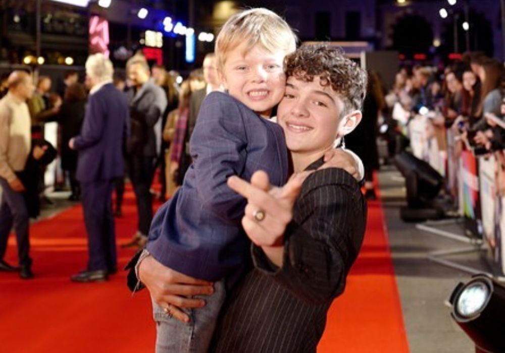 Noah Jupe carrying Jacobi Jupe in his arms.