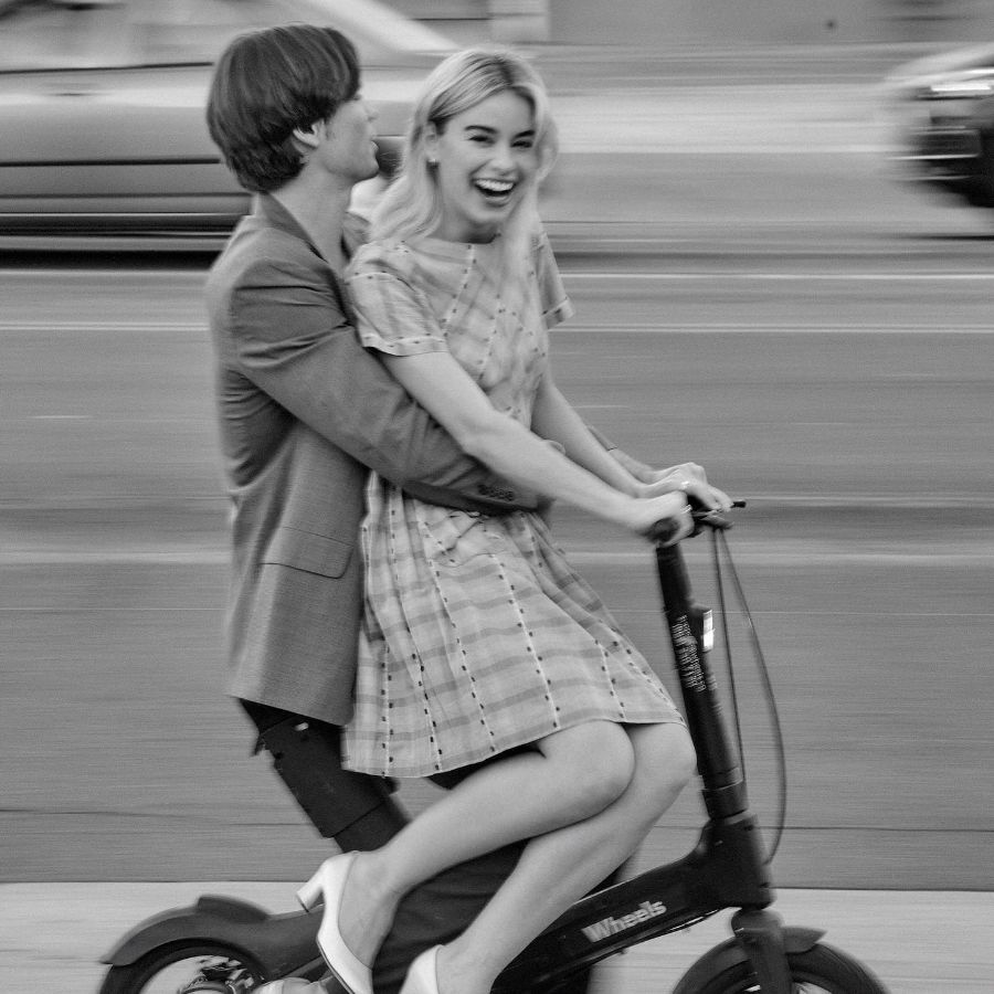 Actor Patrick Luwis and Elle Chapman riding scooter.